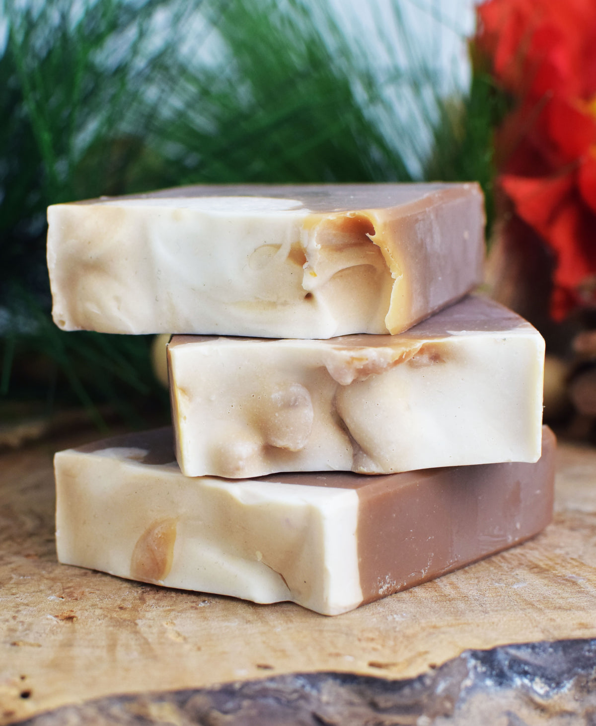 Three bars of soap stacked on a wooden surface with a natural background