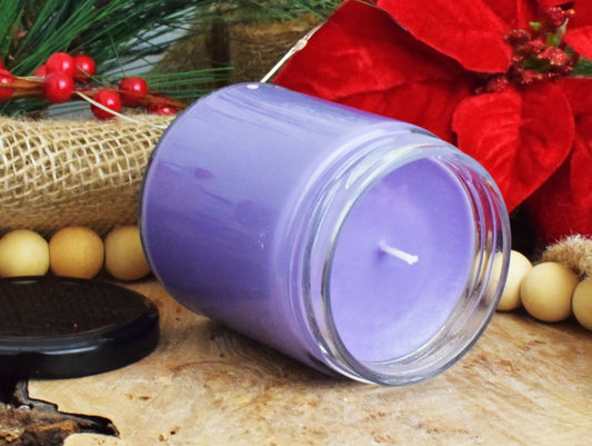 Purple candle in a glass jar with Christmas decorations in the background
