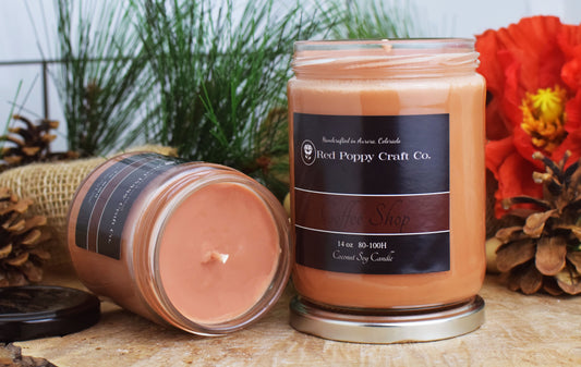 Two coffee shop candles from Red Poppy Craft Co. on a wooden surface with decorative elements.