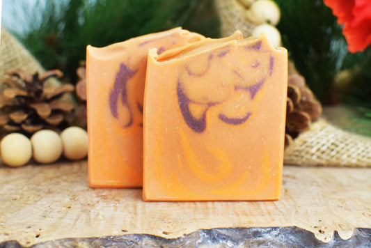 Two orange soap bars with purple designs on a rustic background