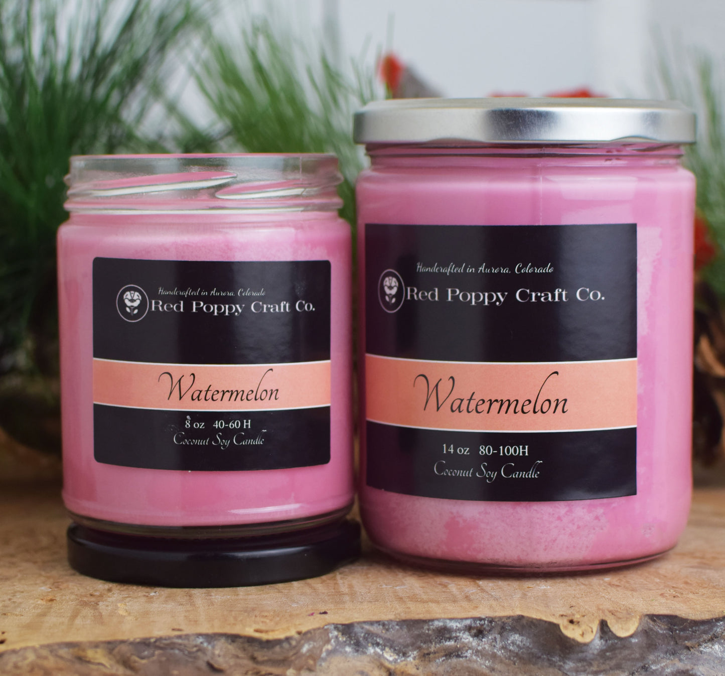 Two pink candles with 'Red Poppy Craft Co.' labels on a wooden surface.